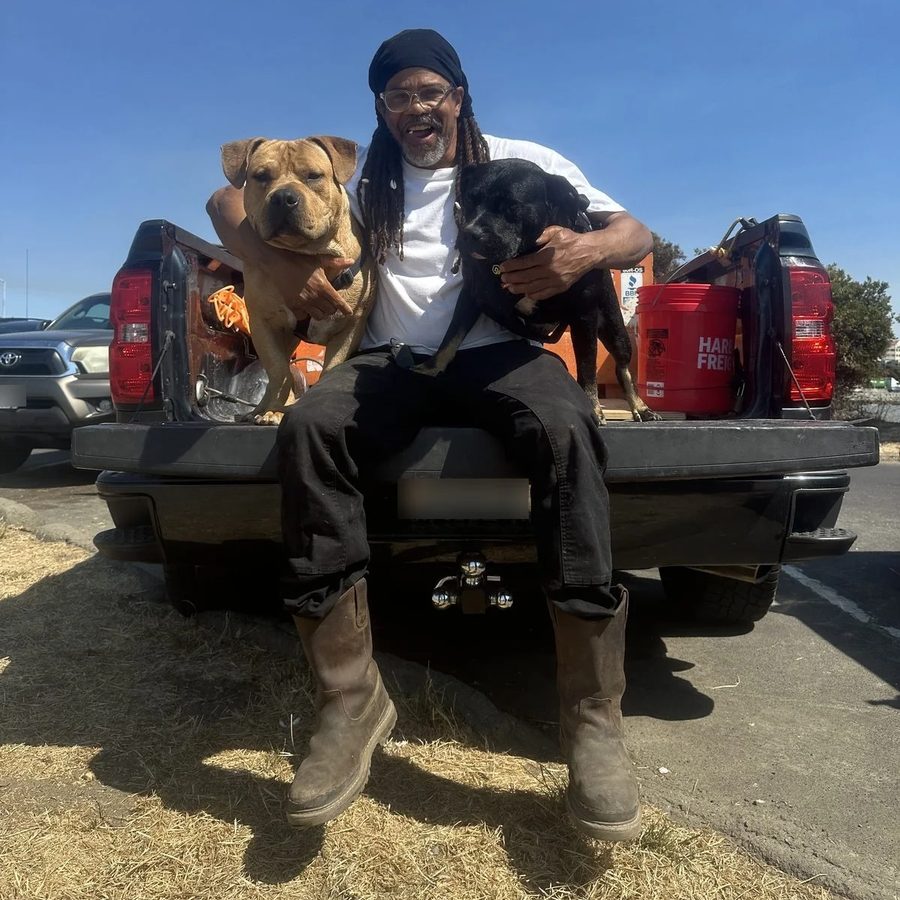 Seanery Donaville, founder of Depth Concrete Inc., sitting on a truck tailgate with his two dogs
